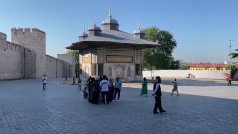 People-outside-the-imperial-gate-of-Topkapi-Palace-against-the-background-of-the-ancient-Fountain-of-Ahmed-III-in-Istanbul,-Turkey