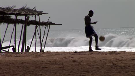 Junger-Nigerianer-Spielt-Bei-Sonnenuntergang-Am-Strand-Fußball