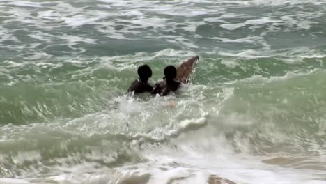 Dos-Niños-Nigerianos-Surfeando-Con-Una-Tabla-Improvisada