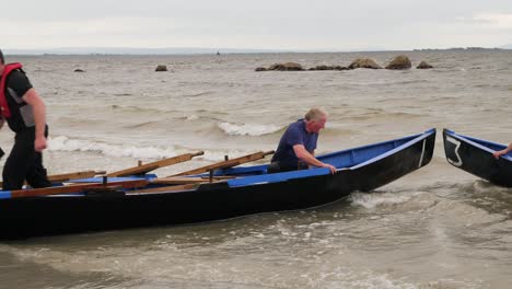 Crew-of-currach-racers-disembark-from-boat-after-rowing-to-sea