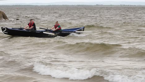 Fuerte-Par-De-Hombres-Remar-Vigorosamente-A-Través-Del-Océano-Abierto-En-Barco-Currach