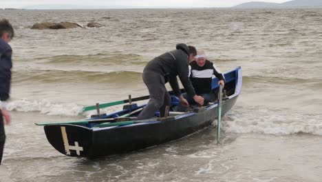 Elder-man-enters-first-as-friends-gather-in-currach-boat-preparing-to-takeoff