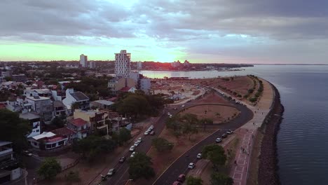 Aerial-view-of-waterfront,-city,-and-highways-of-Posadas,-Misiones,-Argentina-at-sunset