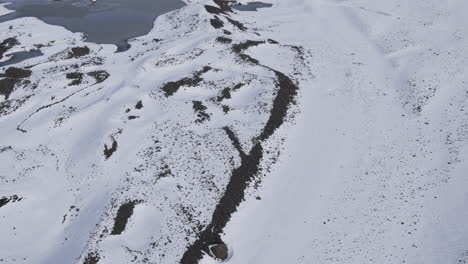 Aufsteigende-Luftaufnahmen-Und-Eine-Kippende-Aufnahme,-Die-Den-Schneebedeckten-Boden-In-Einem-Gebirgstal-In-Island-Zeigt