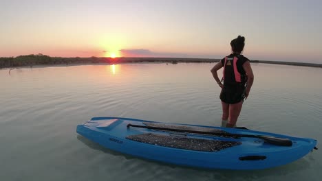 young-solo-female-woman-enjoying-the-sunset-over-a-blue-lake-with-paddle-board-in-Bacall-Mexico-holiday-destination