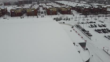 Experience-the-serene-beauty-of-a-snowy-parking-lot-in-winter-as-a-drone-soars-high,-capturing-breathtaking-aerial-views