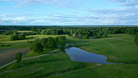 Luftdrohnenaufnahme-Eines-Ländlichen-Bauernhofs-Mit-Teich-Und-Wunderschönem-Himmel