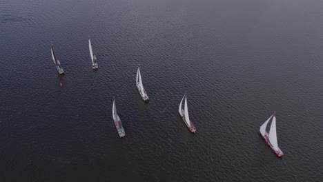 Skutsje-classic-sailboats-sailing-at-tjeukemeer-lake,-aerial