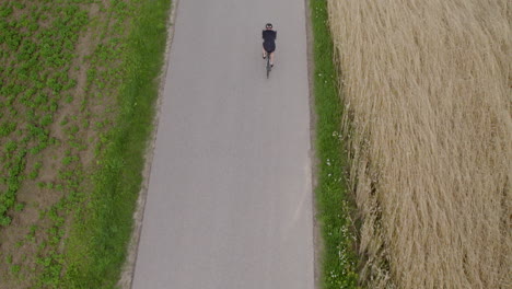A-top-down-drone-shot-of-a-cyclist-riding-on-an-empty-narrow-asphalt-path