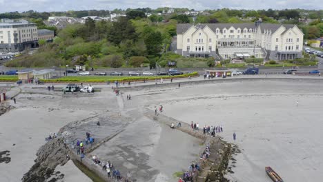 Drone-pulls-back-revealing-stunning-view-of-spectators-at-ladies-beach-tidepools,-galway-ireland