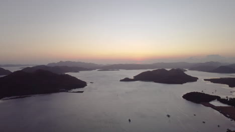 Cinematic-aerial-footage-of-the-sunset-over-the-ocean-with-boats,-mountains-and-beaches-in-focus,-Tiltin-Down,-Palawan,-Philippines,-Drone