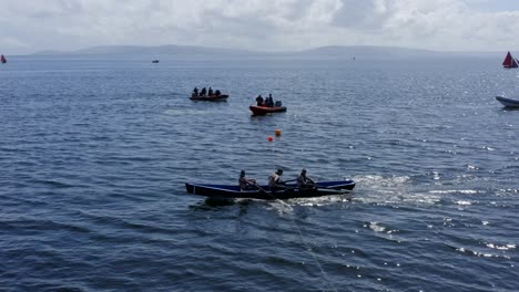 Right-to-left-tracking-of-currach-boats-crossing-finish-line-in-open-ocean