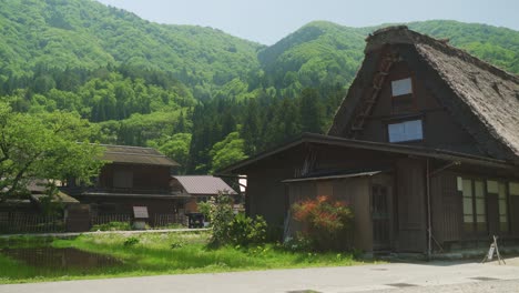 Malerisches,-Idyllisches,-Traditionelles-Gassho-Zukuri-Dorfhaus-Mit-Strohdach-In-Shirakawago-Mit-Bewaldetem-Grünen-Hügel-Im-Hintergrund