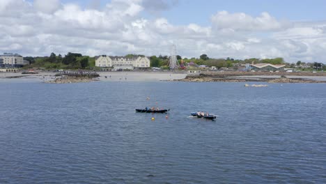 Drone-push-in-above-currach-boats-approaching-start-line-buoys