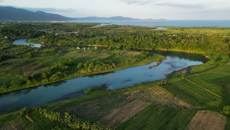 Drone-Panorámico-Que-Se-Eleva-Sobre-Las-Tierras-De-Cultivo-Rurales-De-Filipinas-Y-El-Río-Pajo,-Amanecer