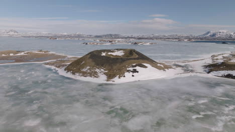 Drohnenaufnahme-Eines-Vulkankraters-Inmitten-Eines-Gefrorenen-Gletschersees-In-Der-Isländischen-Landschaft