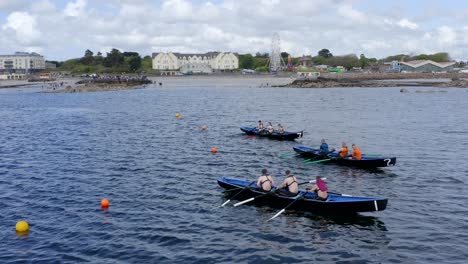 Currach-Bootsrennfahrer-Und-Männer-Sitzen-Bereit-Zum-Rudern-Vor-Dem-Ladies-Beach-In-Galway,-Irland