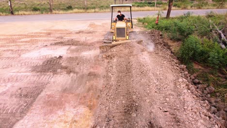 Young-worker-driving-a-grader-to-level-the-ground-in-the-construction-of-a-residential-house