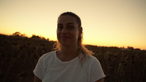 first-wide-shot-of-a-woman-in-an-orange-sunset-looking-at-the-camera-and-smiling