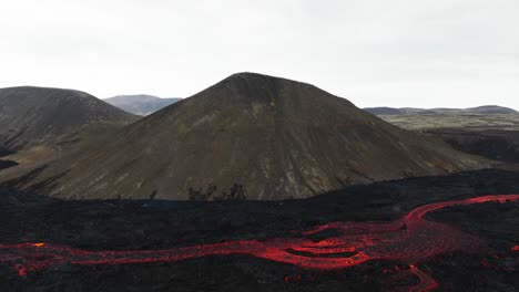 Aerial-landscape-view-over-a-lava-stream-coming-from-the-volcanic-eruptions-at-Litli-Hrutur,-Iceland,-with-smoke-coming-up