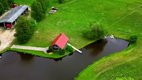 Iconic-rural-homestead-near-water-pond,-aerial-orbit-zoom-in-view