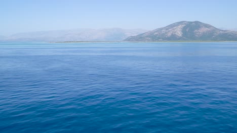 Aufnahme-Des-Meereshorizonts-Mit-Blauem-Meerwasser-Und-Berghintergrund