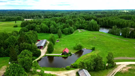 Green-landscape-and-small-homestead-on-lake-of-small-pond,-aerial-view