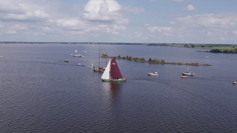 Wide-shot-of-Tjeukemeer-with-classic-sailing-boats-cruising-at-summer,-aerial