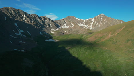 Aerial-cinematic-drone-early-morning-sunrise-trailhead-Grays-and-Torreys-14er-Peaks-Rocky-Mountains-Colorado-stunning-landscape-view-mid-summer-green-beautiful-snow-on-top-forward-zoomed-in-movement