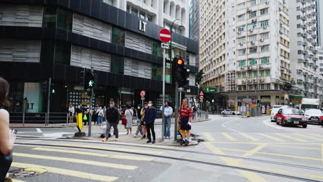 Static-shot-of-people-crossing-a-busy-intersection-with-traffic-in-Hong-Kong,-Asia