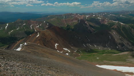Aerial-cinematic-drone-early-morning-hiking-trail-Grays-to-Torreys-14er-Peaks-looking-at-Loveland-Pass-Colorado-stunning-landscape-view-mid-summer-green-beautiful-snow-on-top-forward-movement