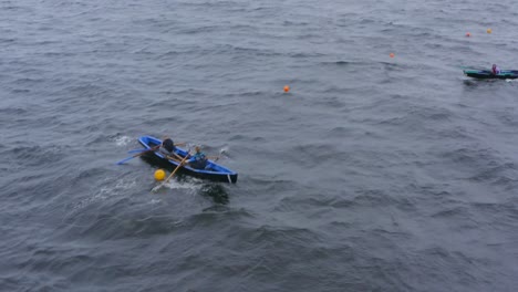 Pair-of-oarsmen-row-Currach-boats-through-buoys-around-course-in-open-ocean