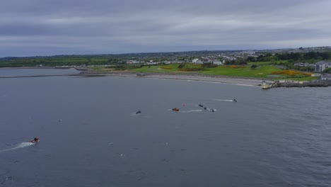 Drone-orbit-around-racing-canoe-boats-off-coast-of-galway-ireland,-gloomy-grey-sky-day
