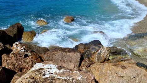 Peaceful-static-shot-of-sea-waves-crashing-on-rocks-and-on-the-beach-in-the-beautiful-coastal-town-on-Varigotti-in-the-north-of-Italy