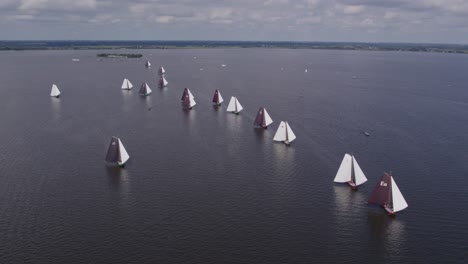 Skutsje-classic-sailboats-on-dutch-calm-lake-ready-for-a-race,-aerial