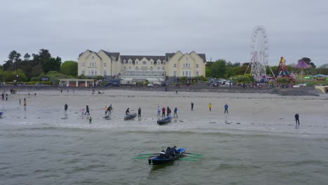 Static-drone-shot-of-Currach-boat-taking-off-from-shore-heading-out-to-ocean