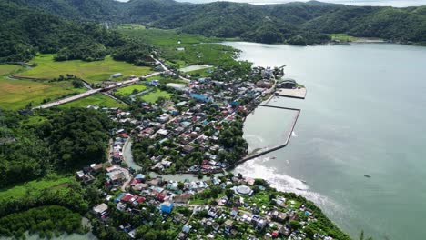 Small-fishing-village-Baras-on-the-Philippines-ocean-coast,-aerial-orbit-around
