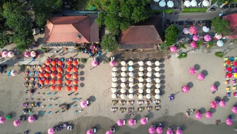 Double-Six-Beach-In-Seminyak,-Bali,-Indonesien-–-Von-Oben-Nach-Unten-Fliegender-Dolly-Aus-Der-Luft-über-Bunte-Mietsonnenschirme-Mit-Liegestühlen-Am-Weißen-Sandstrand