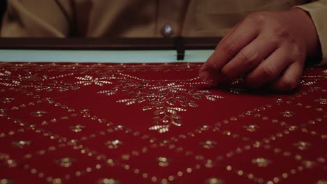 handcrafting-traditional-red-headscarf-shawl-keringkam-using-embroidery-with-gold-threads-intricately