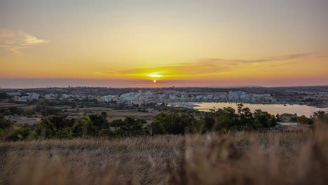 Timelapse-shot-of-sun-setting-over-a-seaside-town-in-Marsaxlokk,-Malta-during-evening-time