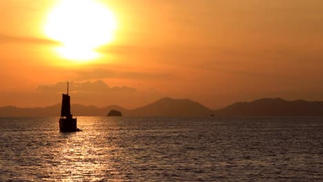 Asiatisches-Segelboot,-Das-An-Einem-Heißen,-Sonnigen-Tag-Auf-Dem-Wasser-Des-Sonnenuntergangs-Schwimmt,-Gerade-Als-Die-Sonne-Für-Den-Abend-Untergeht