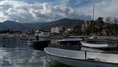 Boats-docked-at-marina-at-sunset,-promenade-and-seaside-town,-Tivat,-Montenegro