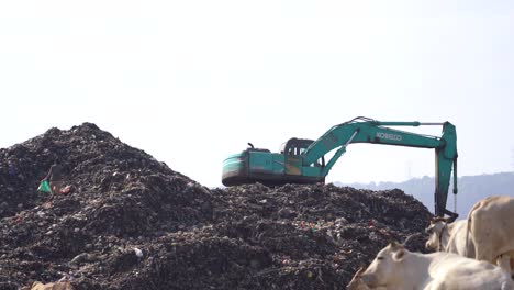 excavator-working-on-tidying-up-mountains-of-garbage-at-the-Piyungan-landfill,-Yogyakarta