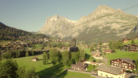 dolly-sideways-right-to-left-following-a-descending-cabin-of-tricable-car-system-Eiger-Express-in-picturesque-Grindelwald,-with-mountain-views