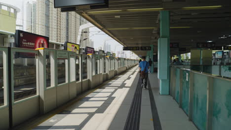 Toma-Dinámica-De-Personas-Esperando-Su-Tren-En-El-Andén-En-Hong-Kong,-Asia