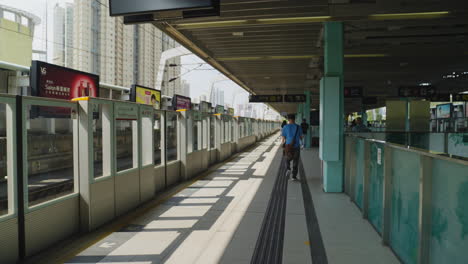 Dynamic-shot-of-people-waiting-for-their-train-on-the-platform-in-Hong-Kong,-Asia