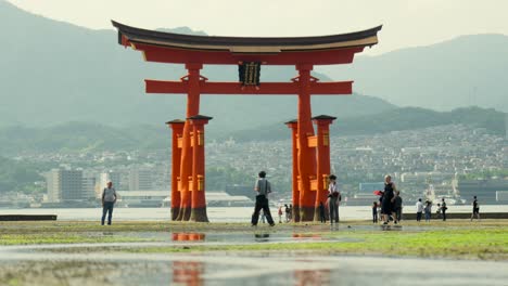 Turista-Visitando-El-Gran-Torii-Gigante-Rojo-Del-Santuario-Del-Templo-Itsukushima-En-La-Isla-De-Miyajima,-Hiroshima,-Japón