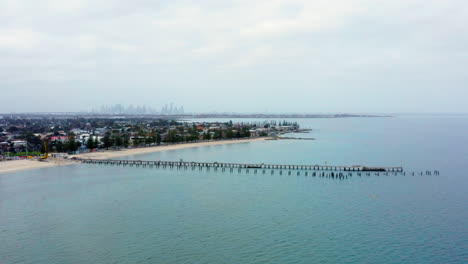 AERIAL-Over-Altona-Beach-and-Pier-With-Melbourne-City-Skyline