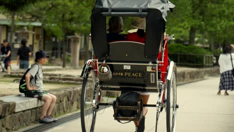 Tour-De-Jin-Rickshaw-En-La-Isla-De-Miyajima-Hiroshima-Japón-Con-Signo-De-Paz-Y-Calle-Con-Turistas