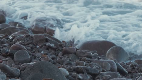 Waves-break-over-smooth-rocks-lining-the-shore-Slow-Motion